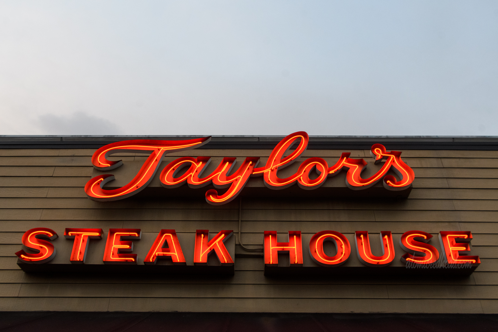 Red neon spells out "Taylor's Steak House"