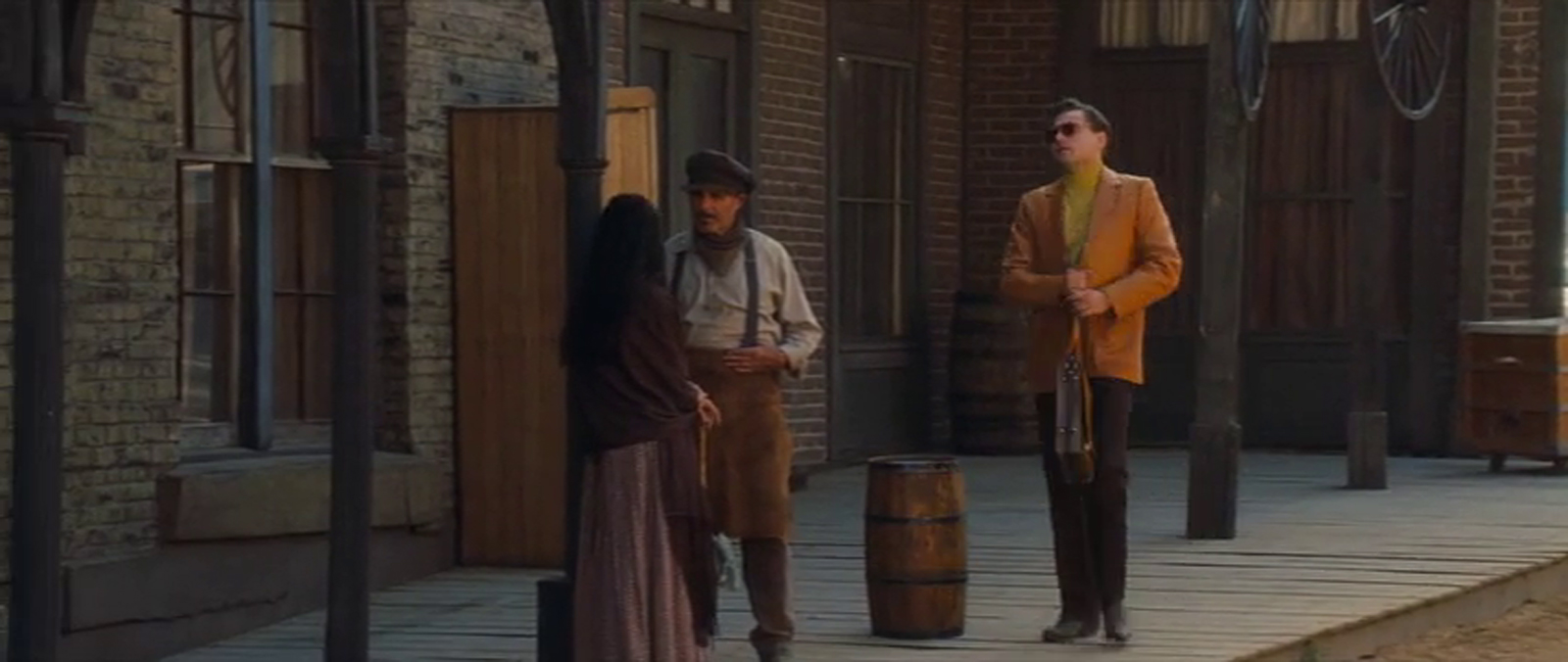 Rick arrives on set, a brick building is behind him. Those around him are already in costume.