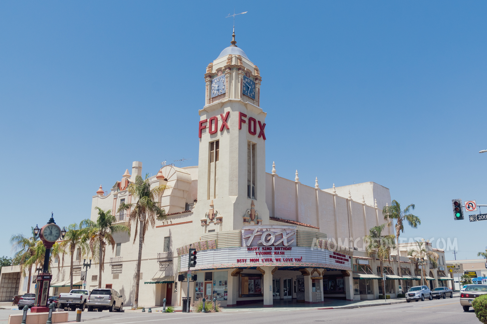 The Fox Theatre, an elegant Spanish Colonial Revival style building with a tall clock tower at its corner, with red letters spelling "Fox" an Art Deco marque curves around the corner with script reading "Fox" in neon.
