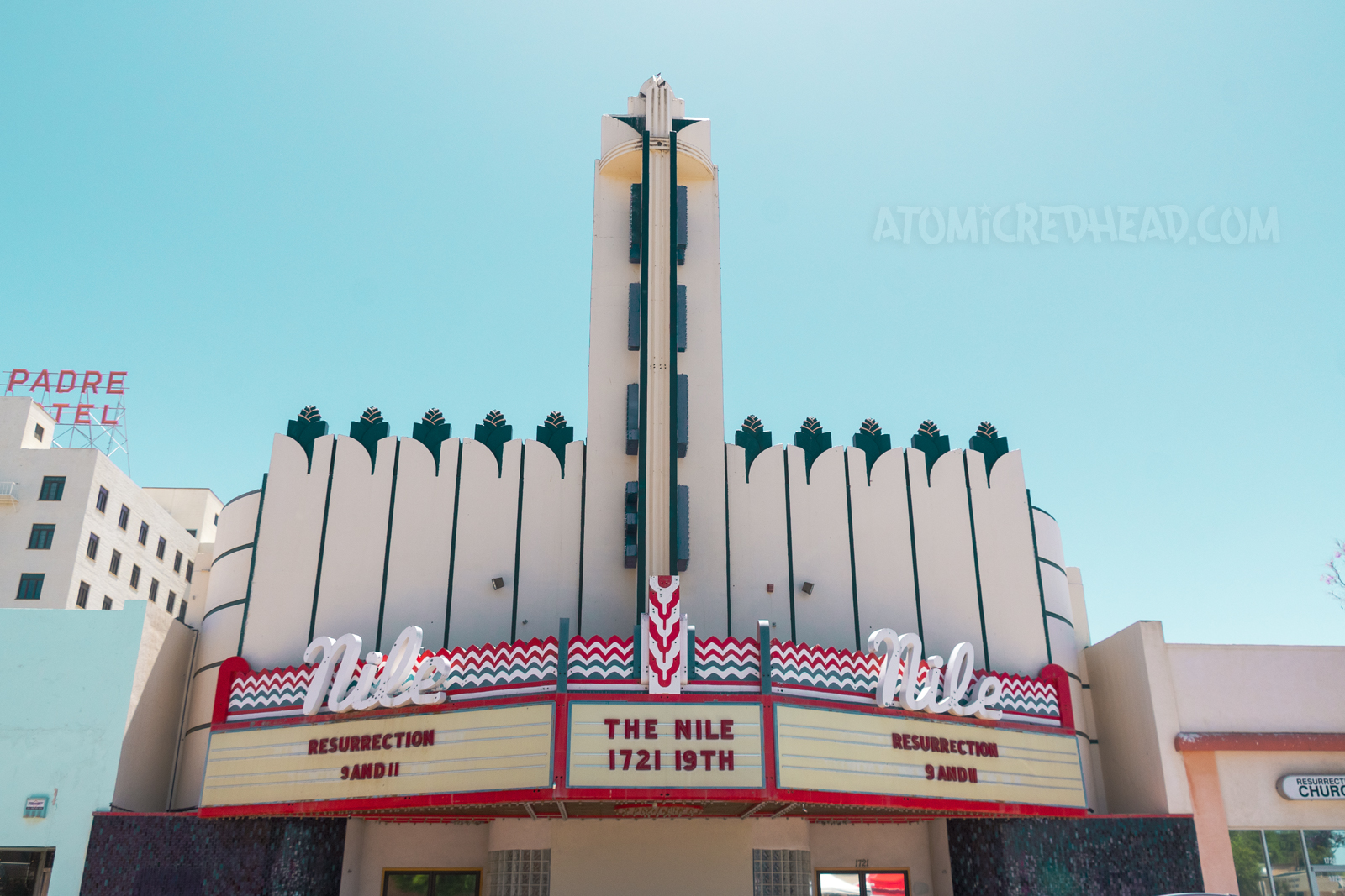 The Nile Theater, an Art Deco style building with a tower in the center reading "Nile" down it in blue letters. The marque features neon and reads "Nile" in cursive white neon.