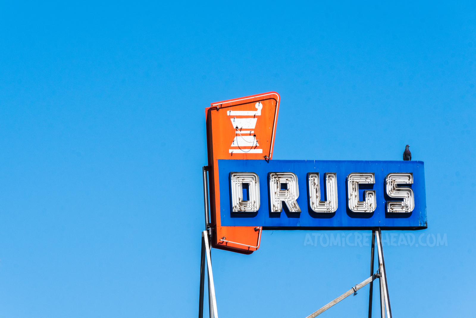 A red, white, and blue neon sign reads "Drugs"
