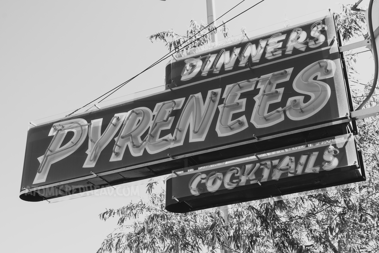 A simple neon sign reads "Dinners Pyrenees Cocktails"
