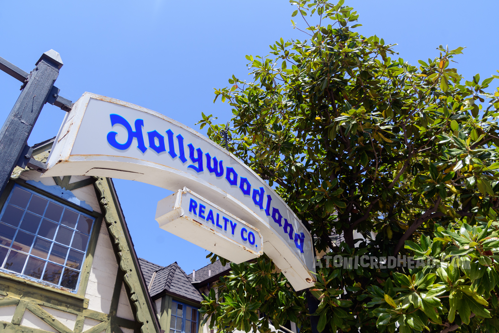 A white arched sign reads "Hollywoodland Realty Co." in gothic blue letters.