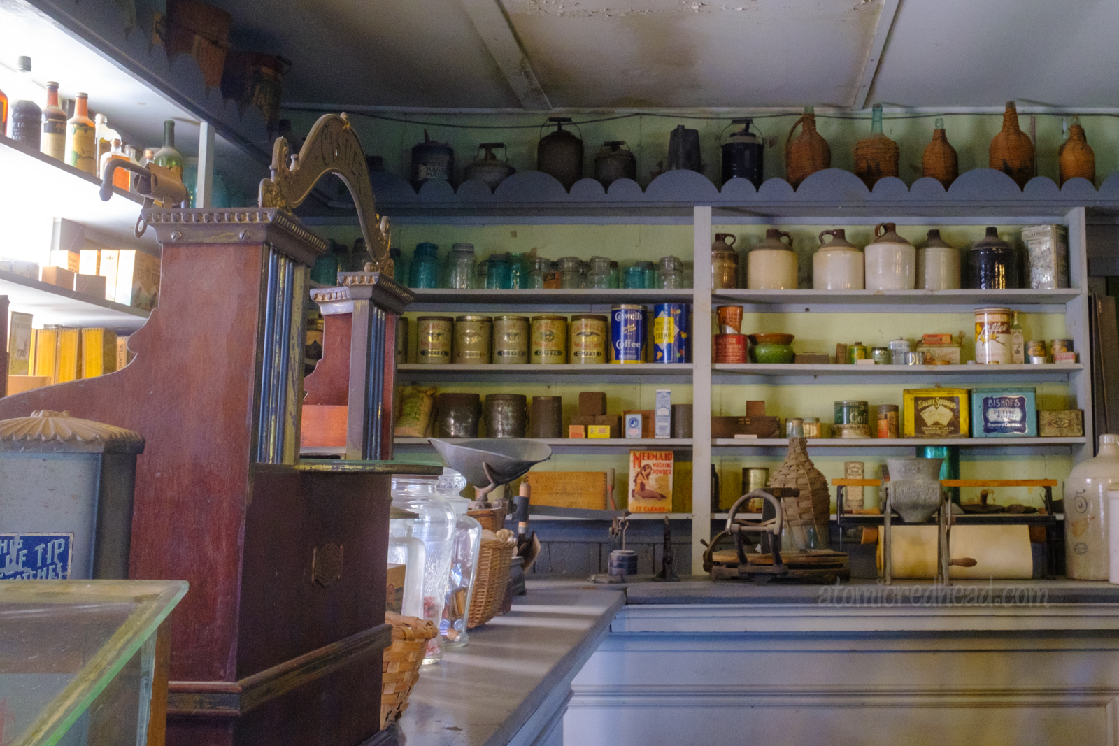 Inside the general store, with shelves stocked with various goods, and a cash register on the left.