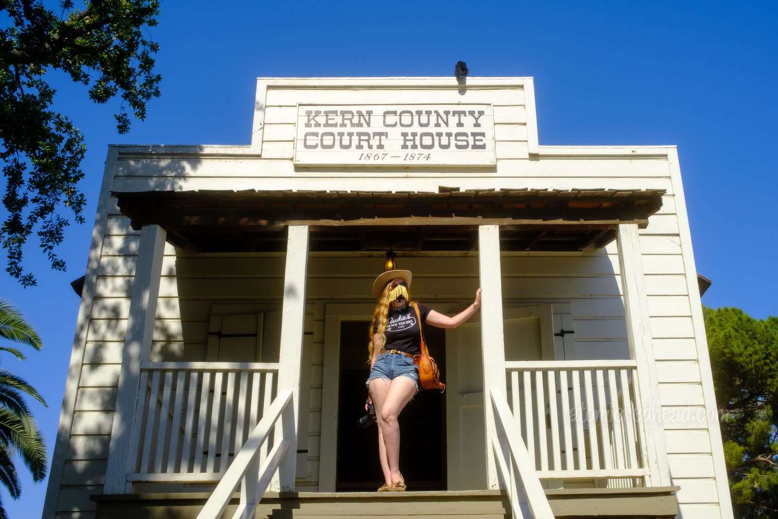 Myself standing on the porch of the old Kern County Court House, a white, old west style building.