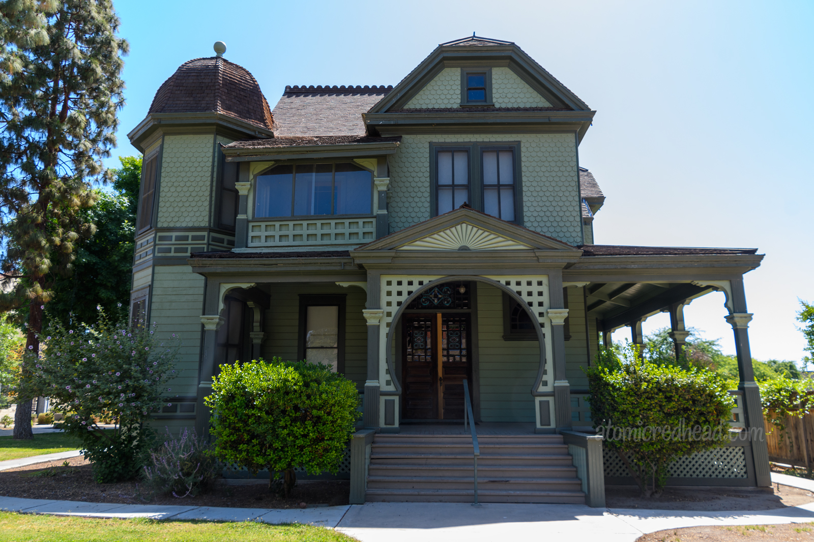 A beautiful Victorian home painted in a sage green with dark green trim.