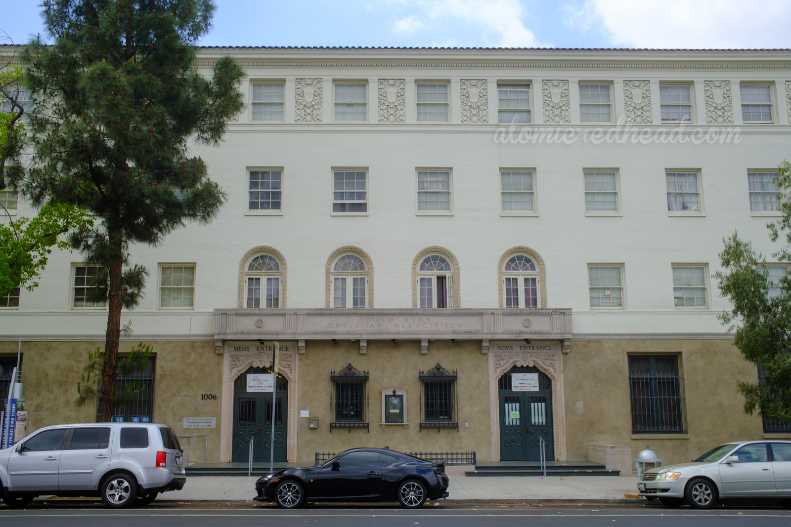 A four story Spanish Colonial Revival building. An etched sign above the doors reads "Young Mens Christian Association." Above the doors, one reads "Mens Entrance" the other says "Boys Entrance"