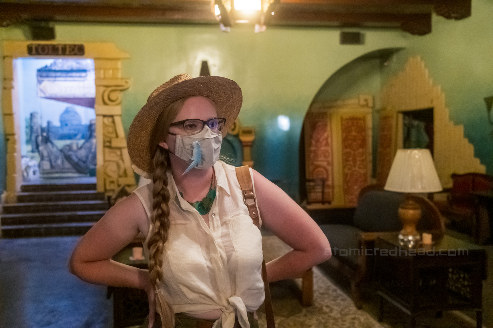Myself, wearing a straw hat, white sleeveless blouse and green shorts, standing in the lobby.