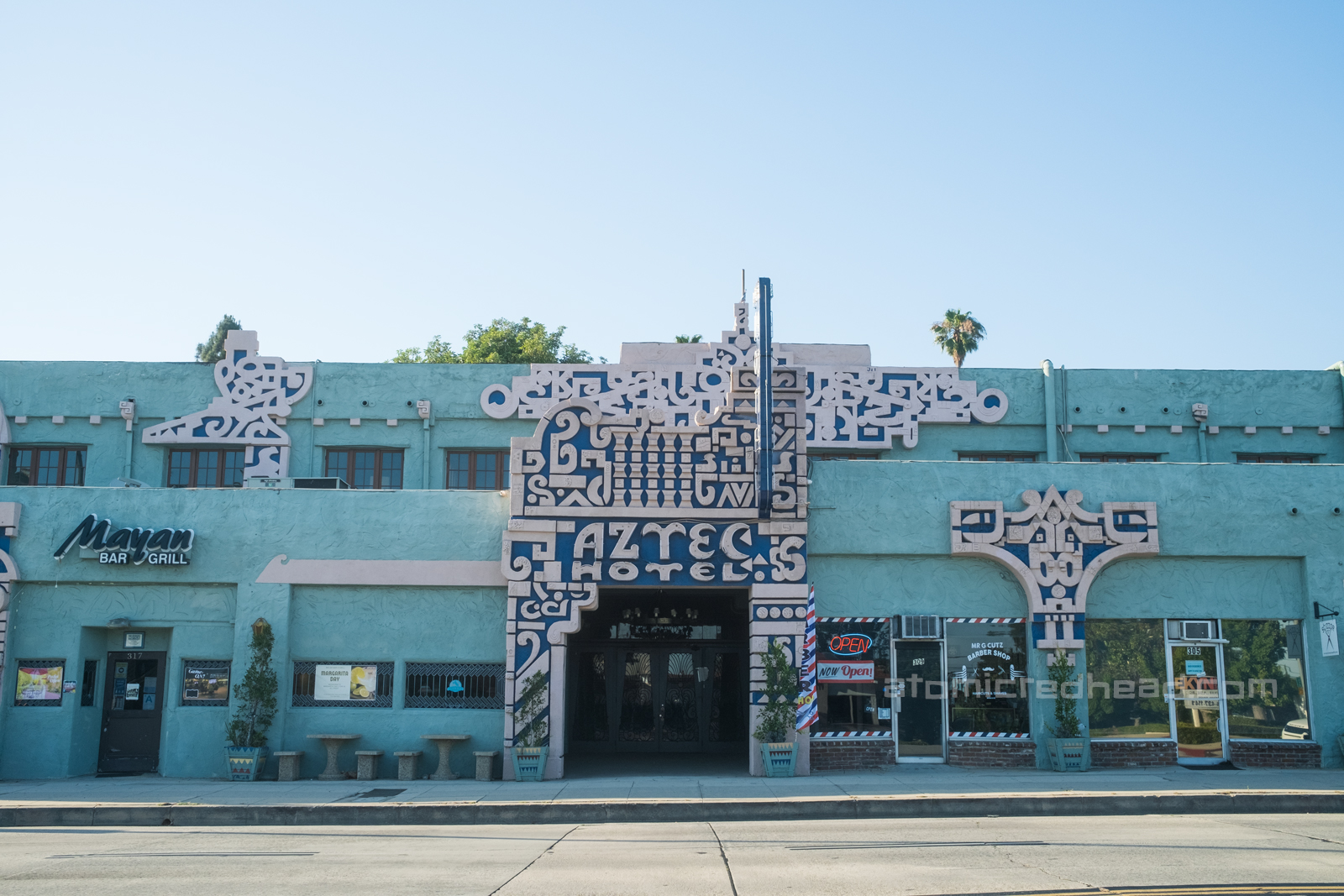 Exterior of the Aztec, a teal painted structure with various Mayan influenced designs along the corners, edges, and doorways.