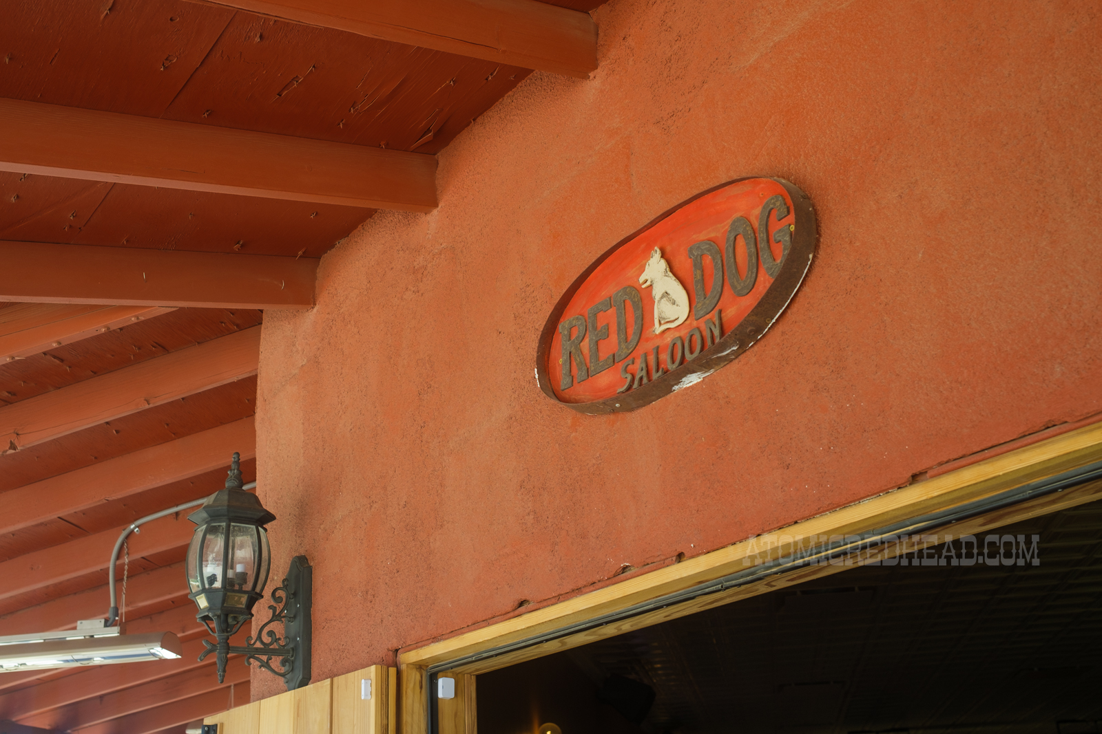 A small metal sign featuring an image of a dog and text reading "Red Dog Saloon"