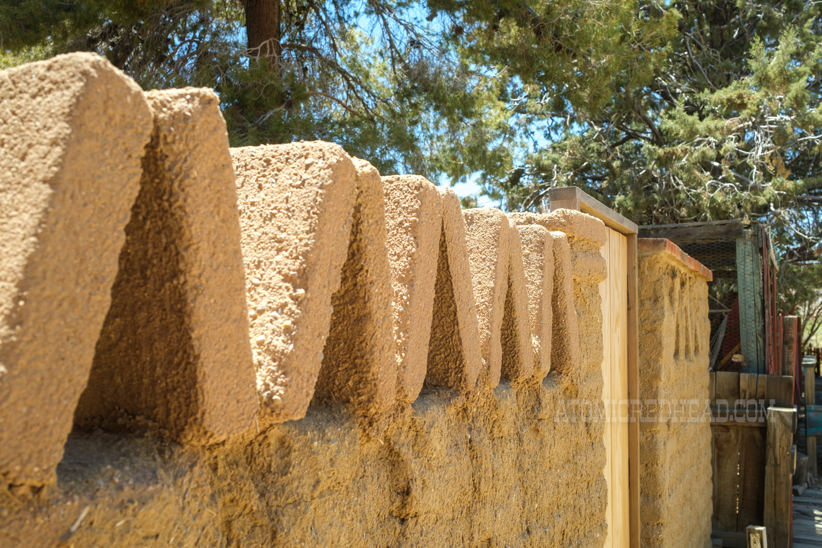 Adobe bricks make up a small wall, at the top the bricks form a zig-zag pattern.