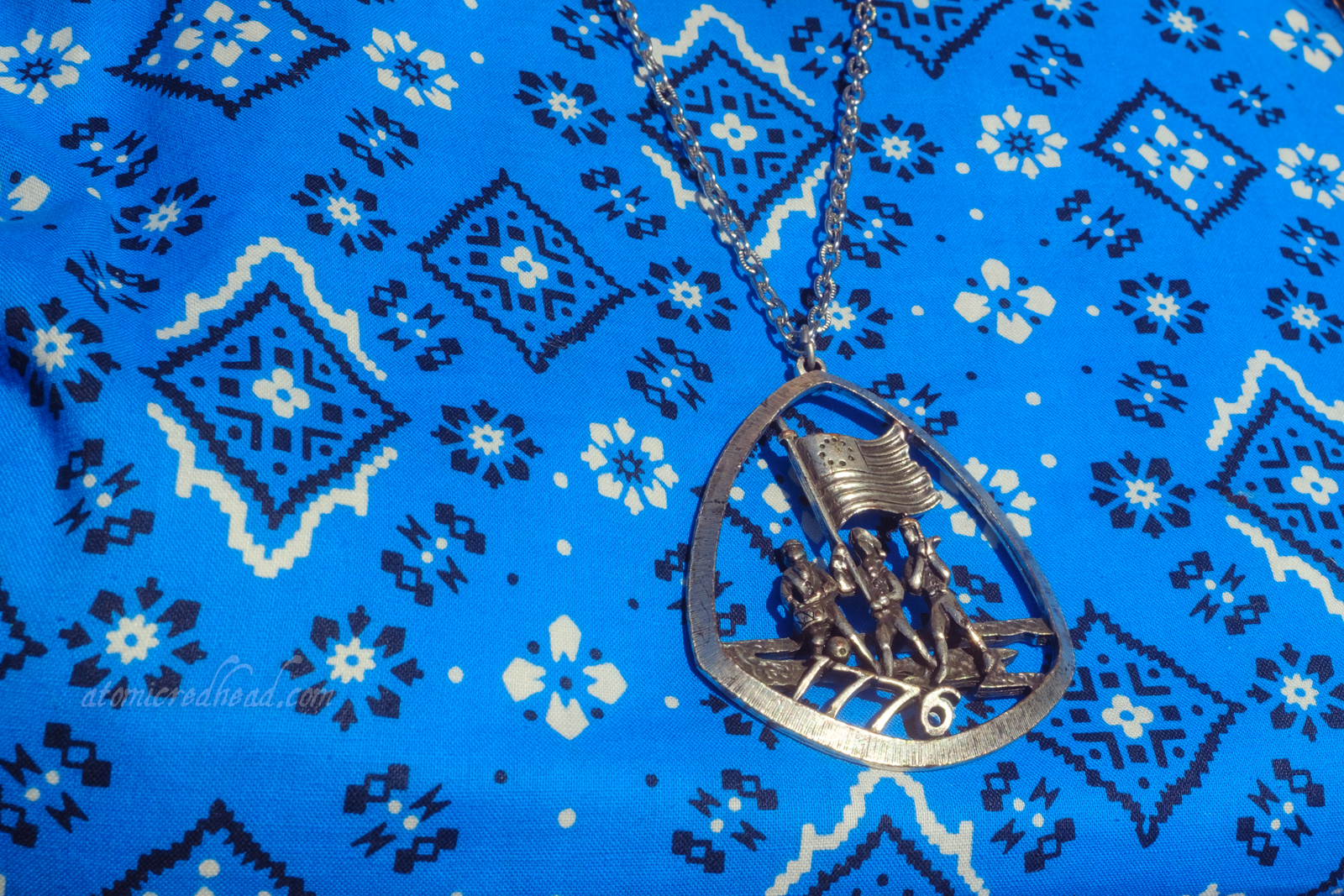 Close-up of my necklace, which features "The Spirit of '76" three men, one carrying the American flag, another a drum, another with a flute. Text reads "1776" along the bottom.