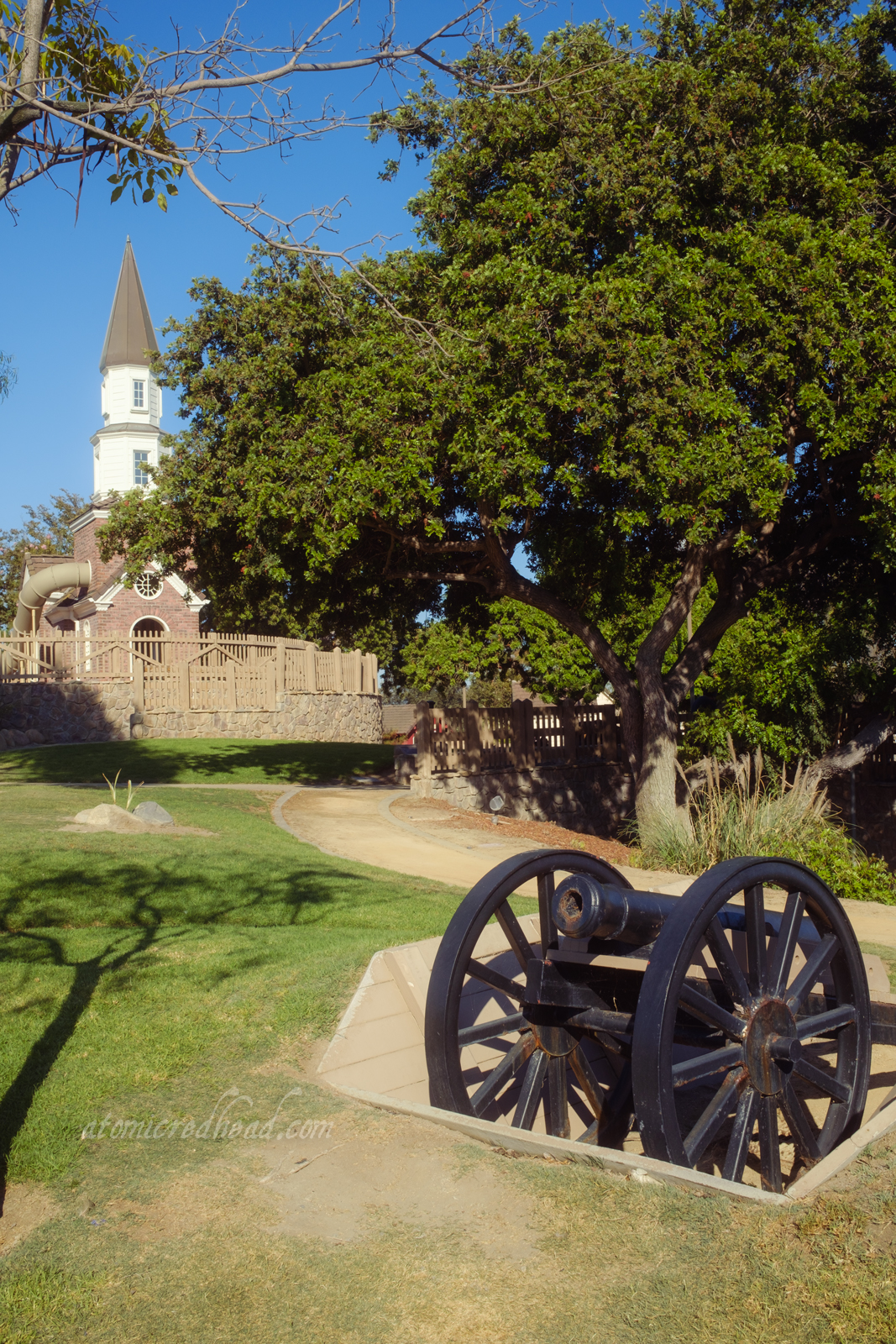A cannon sit in the foreground while the small replica of Old North Church stands in the background, a brick and white building with a steeple.