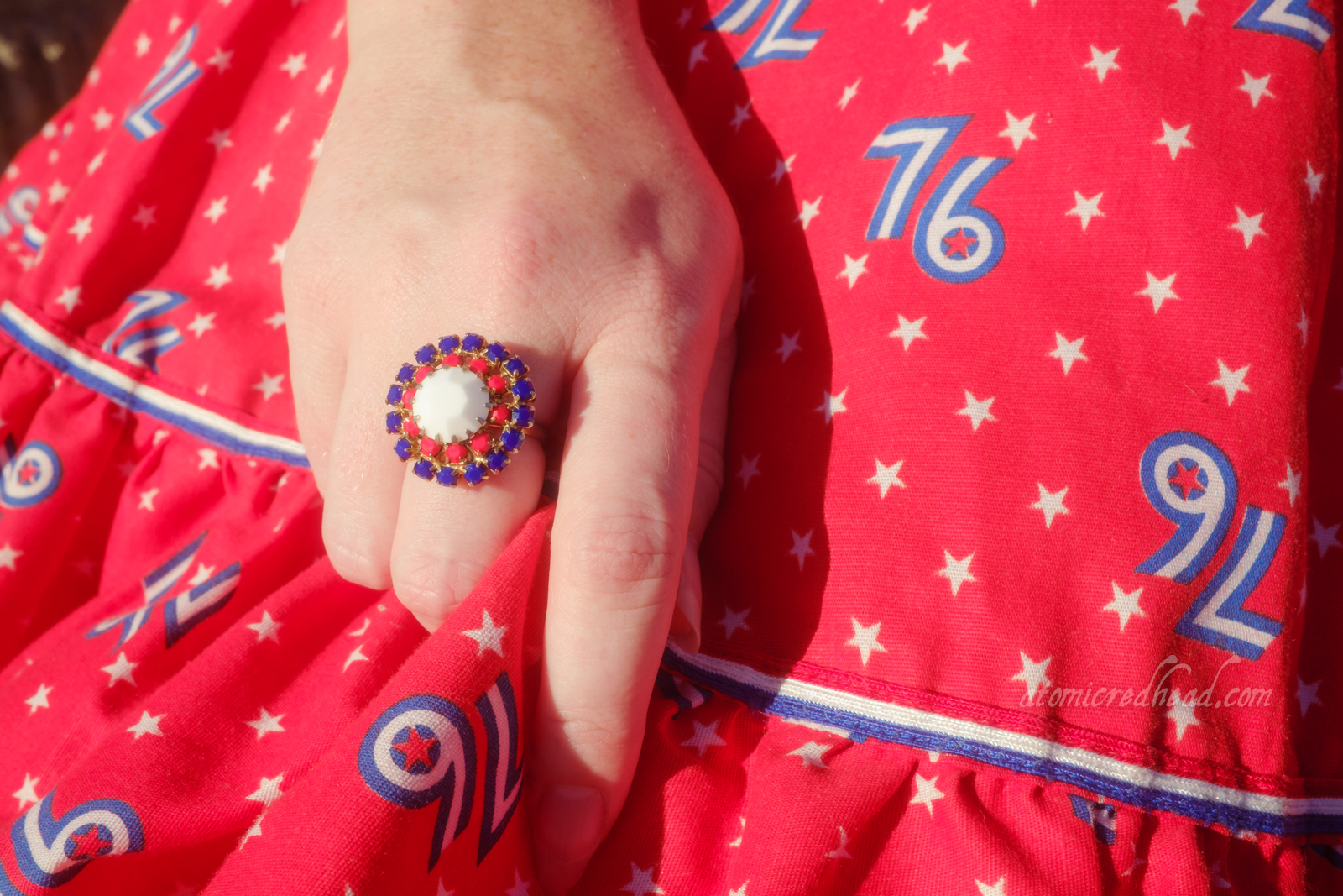 Close-up of my hand, wearing a ring made up of red, white, and blue stones.