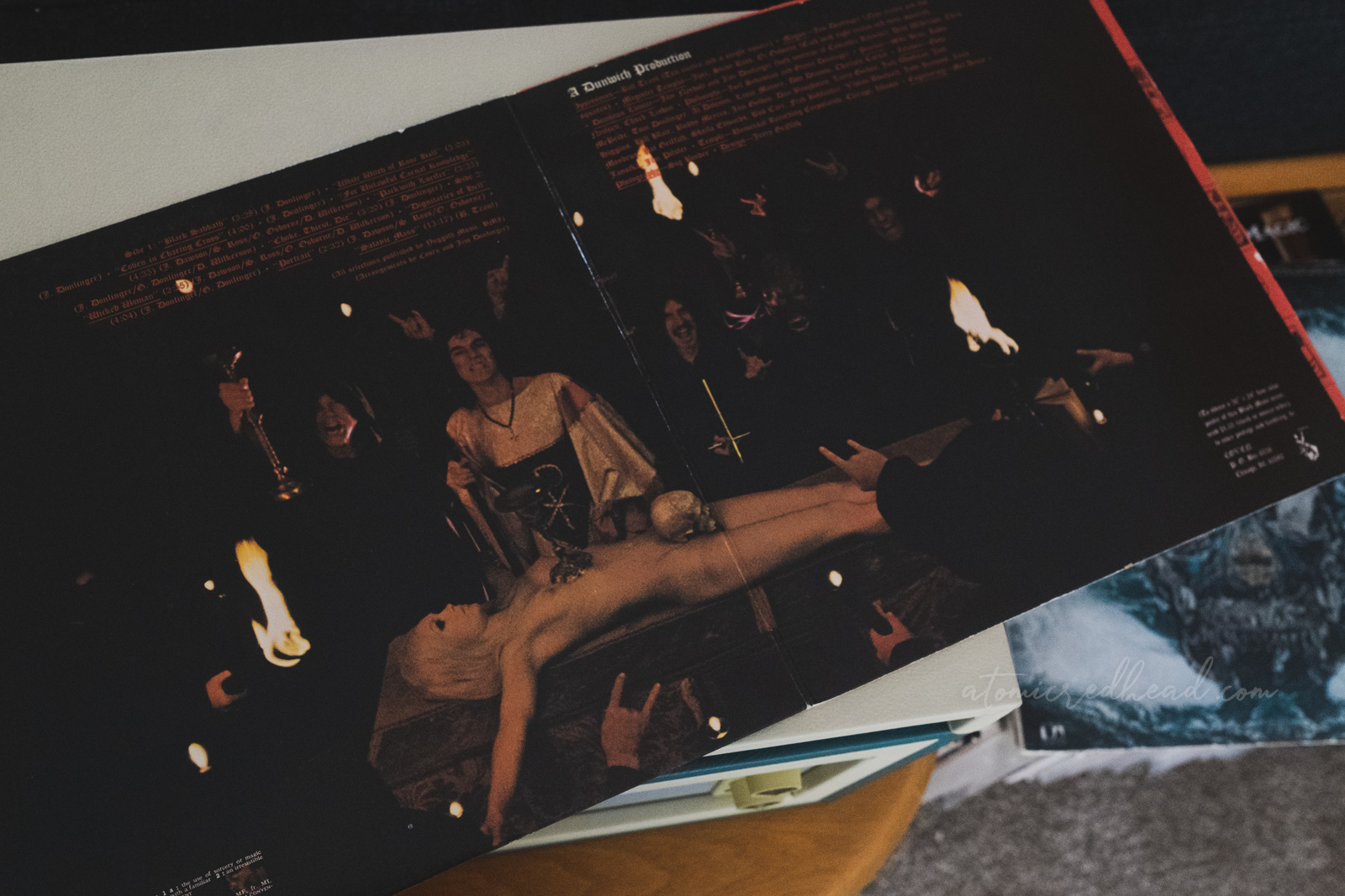 Gatefold of the album, which features the blonde woman laid naked on the red alter, a skull covers her crotch. Men in black robes stand behind the alter, some have their hands raised with the sign of the horns.