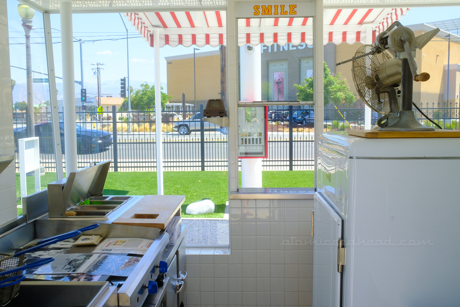 Inside the replica, on the left is the food prep area and friers, the window to serve the customers is in the middle, with yellow letters above reading "Smile" and to the left is a vintage white ice box.