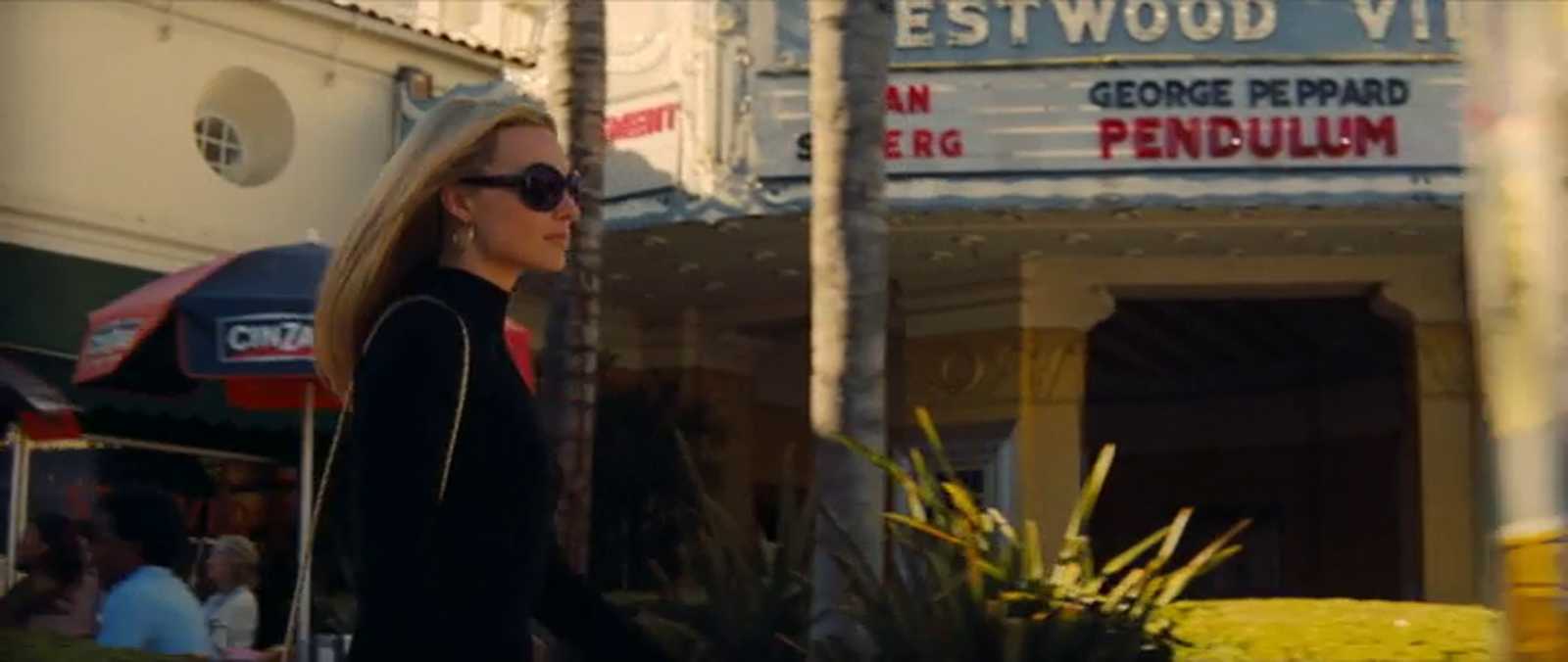 Margo Robbie as Sharon Tate walks was the Fox Westwood Village Theater, the neon marquee visible in the background.