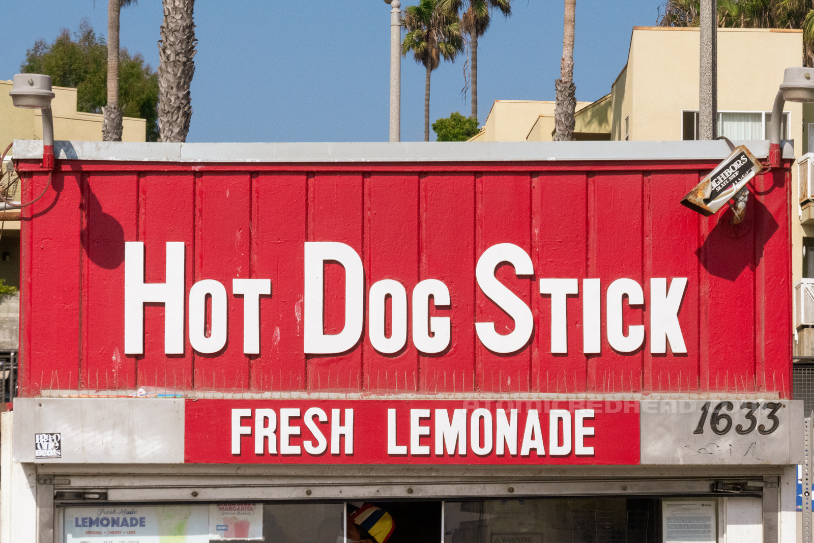 Close-up of the front of the building, reading "Hot Dog Stick Fresh Lemonade" in white letters.