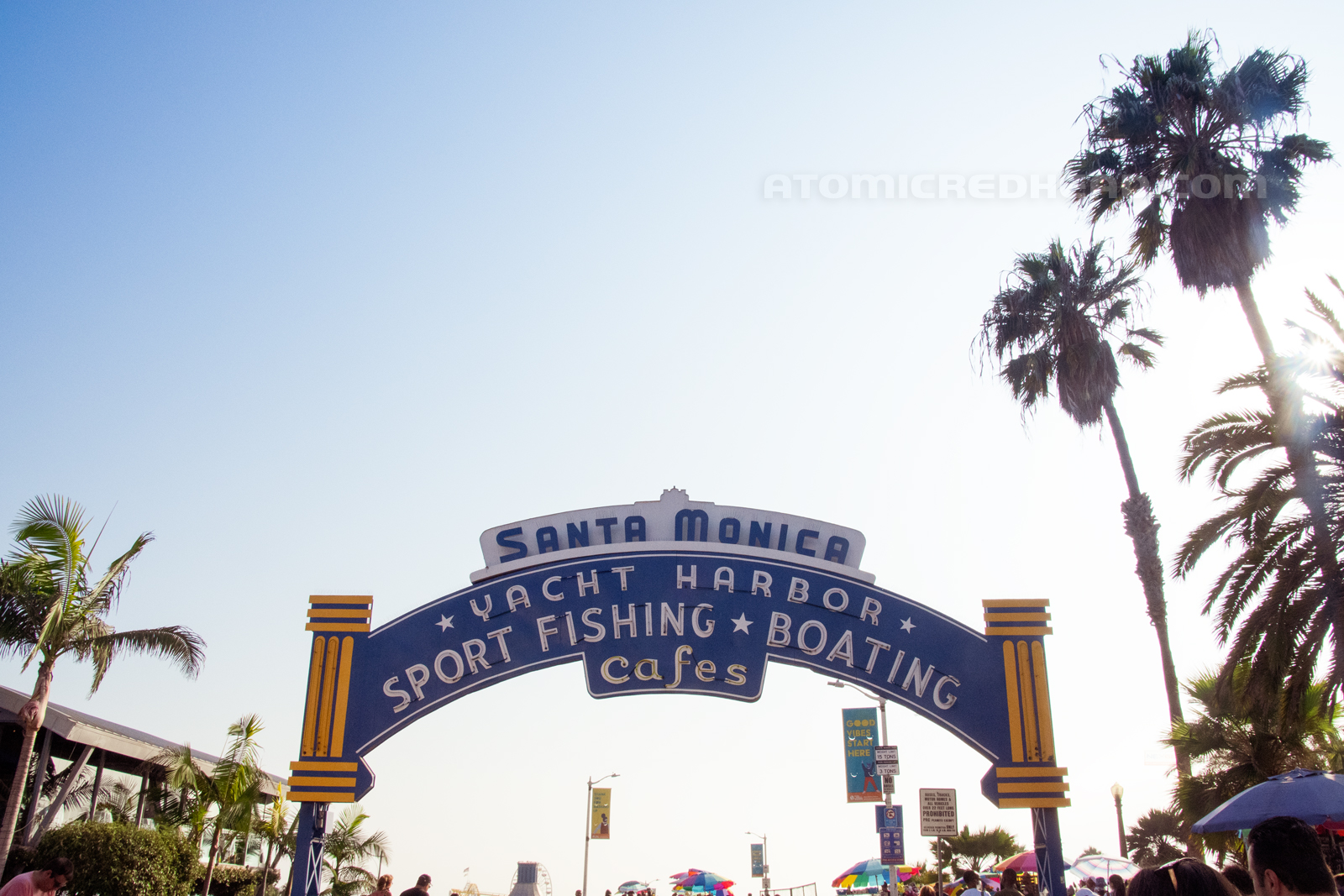 Santa Monica Pier sign, blue with white letters reading "Santa Monica Yacht Harbor Sport Fishing Boating Cafes/"