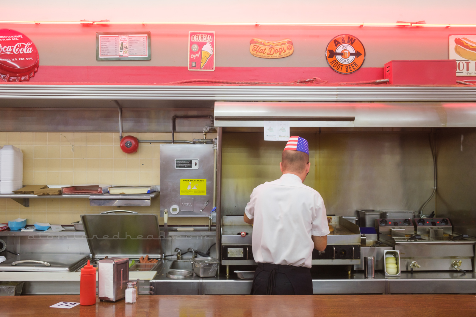 A man works at the cook top behind the counter.