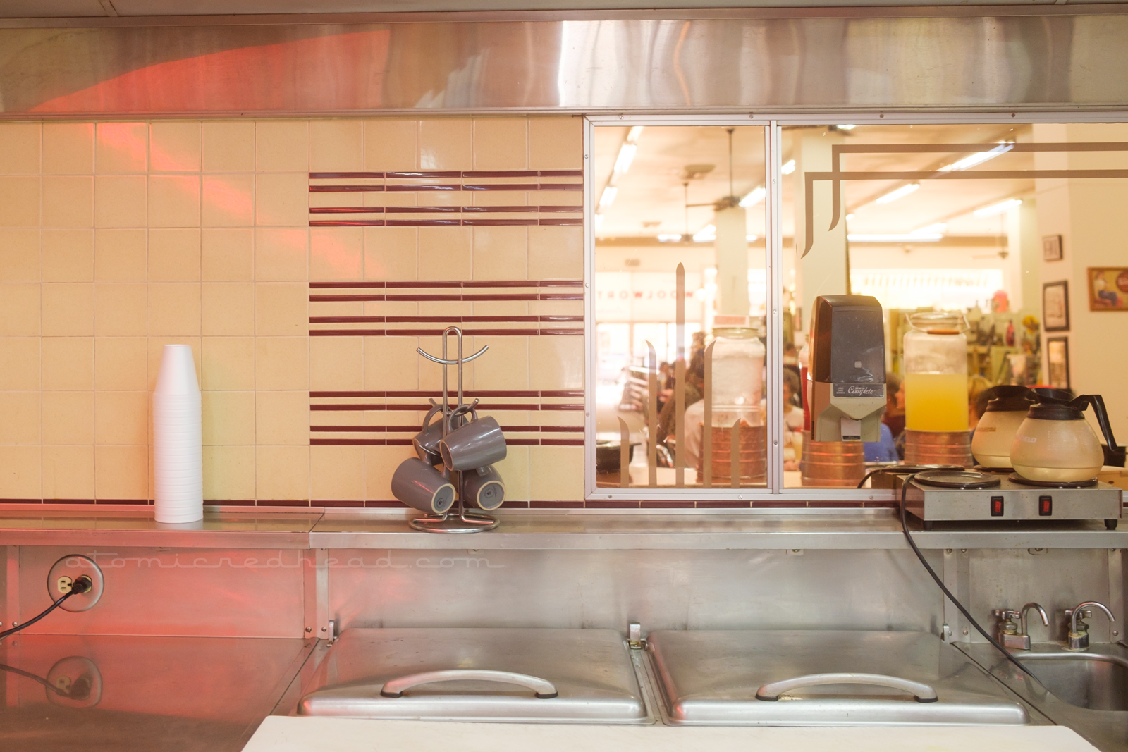 Cream tile backsplash with brown detail tiles and a mirror sit above the work counter.