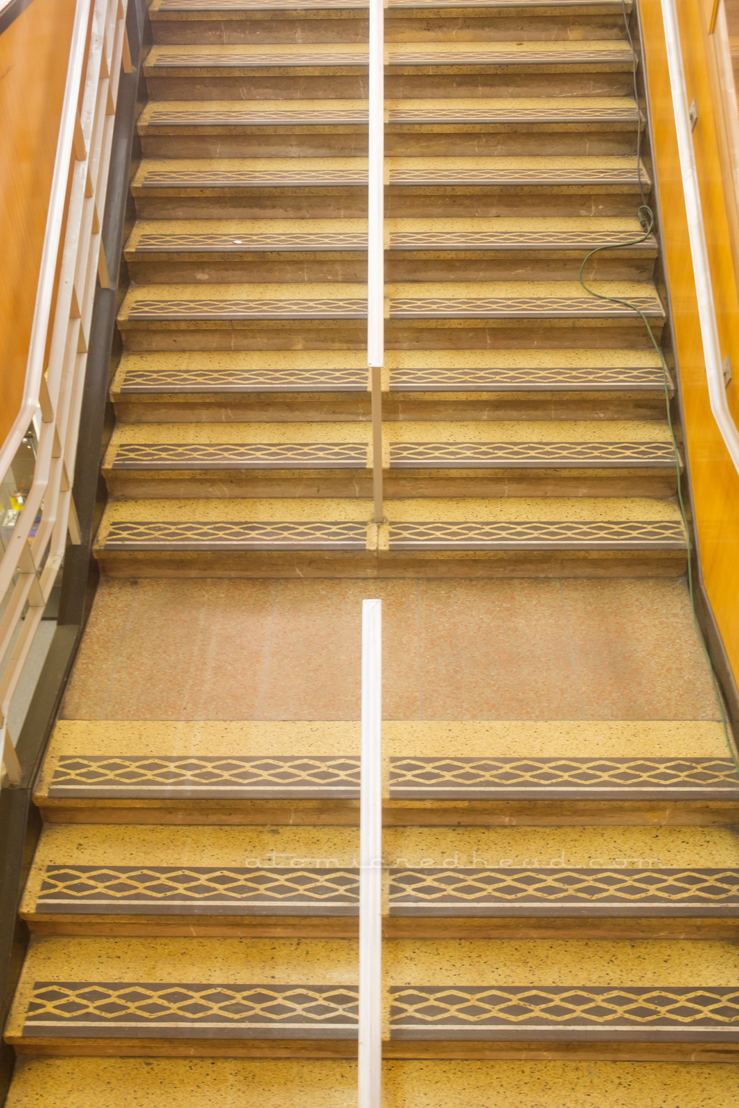 Yellow and brown terrazzo staircase down to the basement with chrome hand rails.