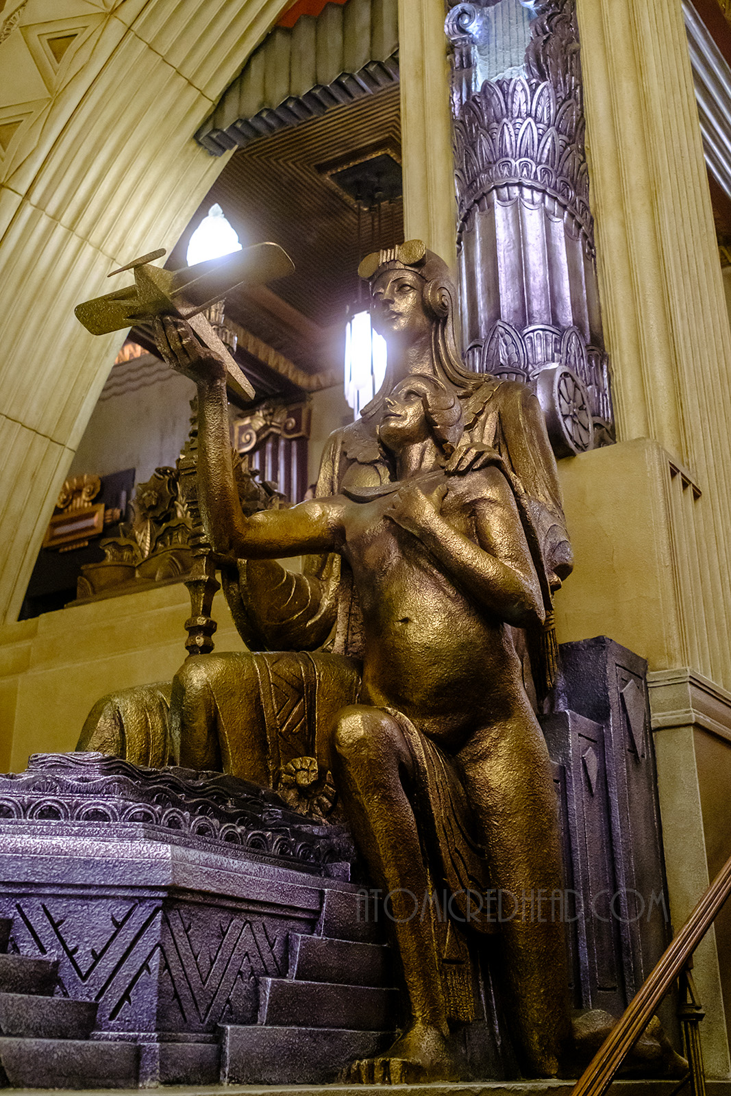 Life size gold Art Deco statue of two people, one holds an airplane model