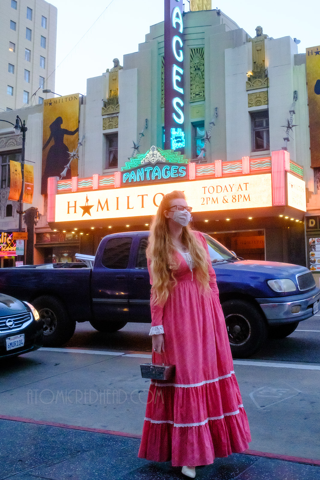 Myself, wearing a red maxi length dress with a small print of tiny leaves, standing in front of the Pantages