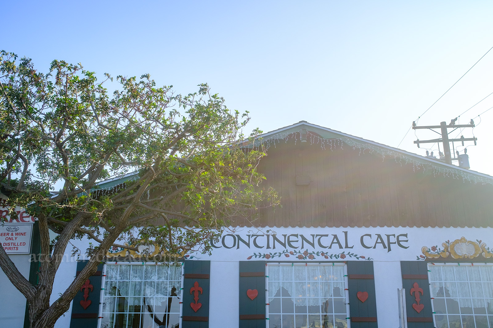 A small chalet style building features green shutters with red hearts in the middle. Painted above the windows reads "Continental Cafe" 