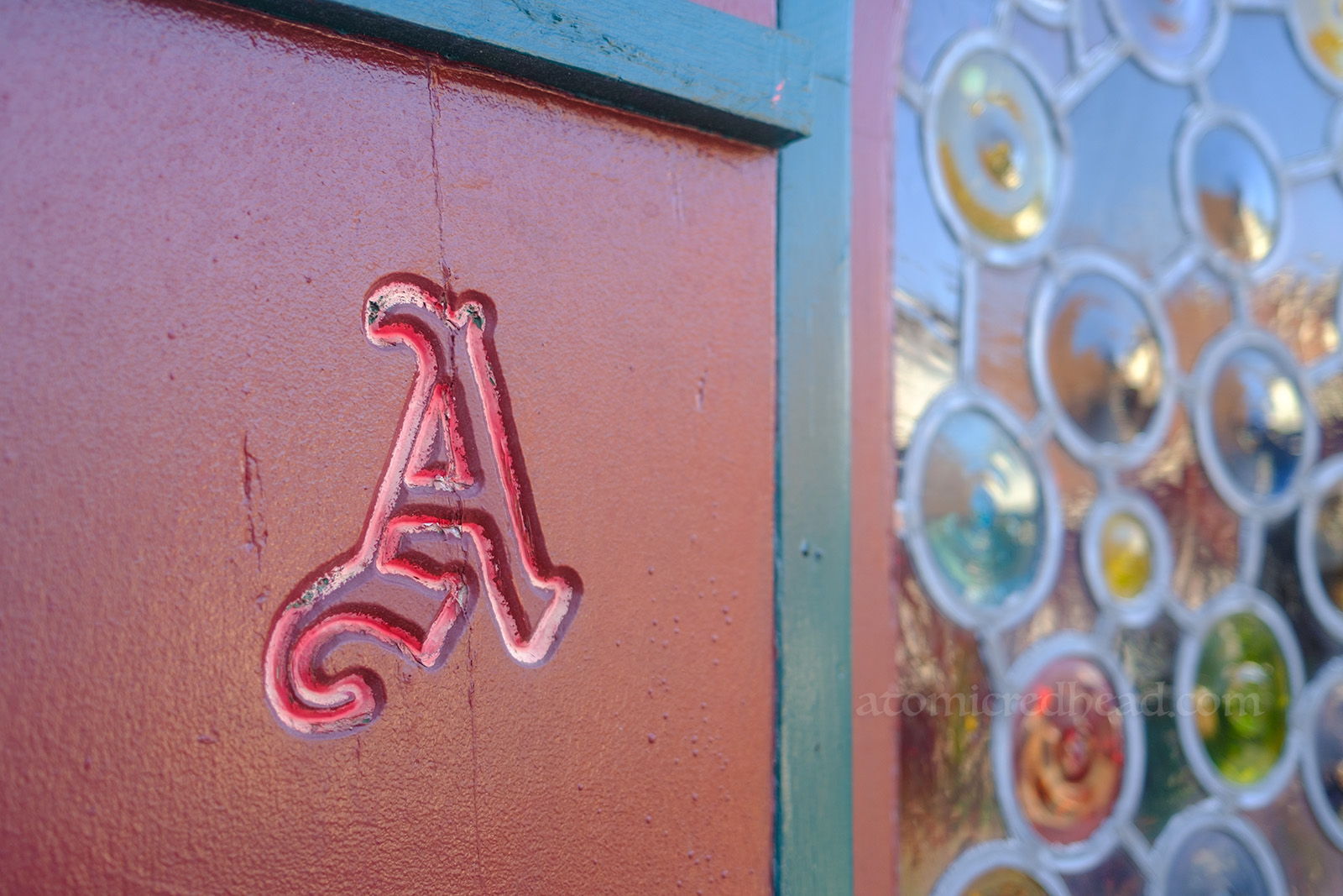 Close-up of a gothic A carved into a shutter.