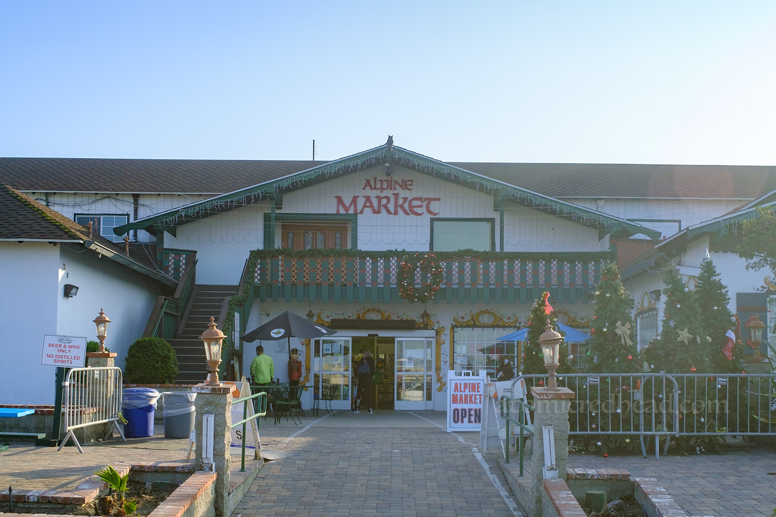 Exterior of Alpine Market, a large, two story chalet style building, a white building with green trim, and red letters spelling "Alpine Market."