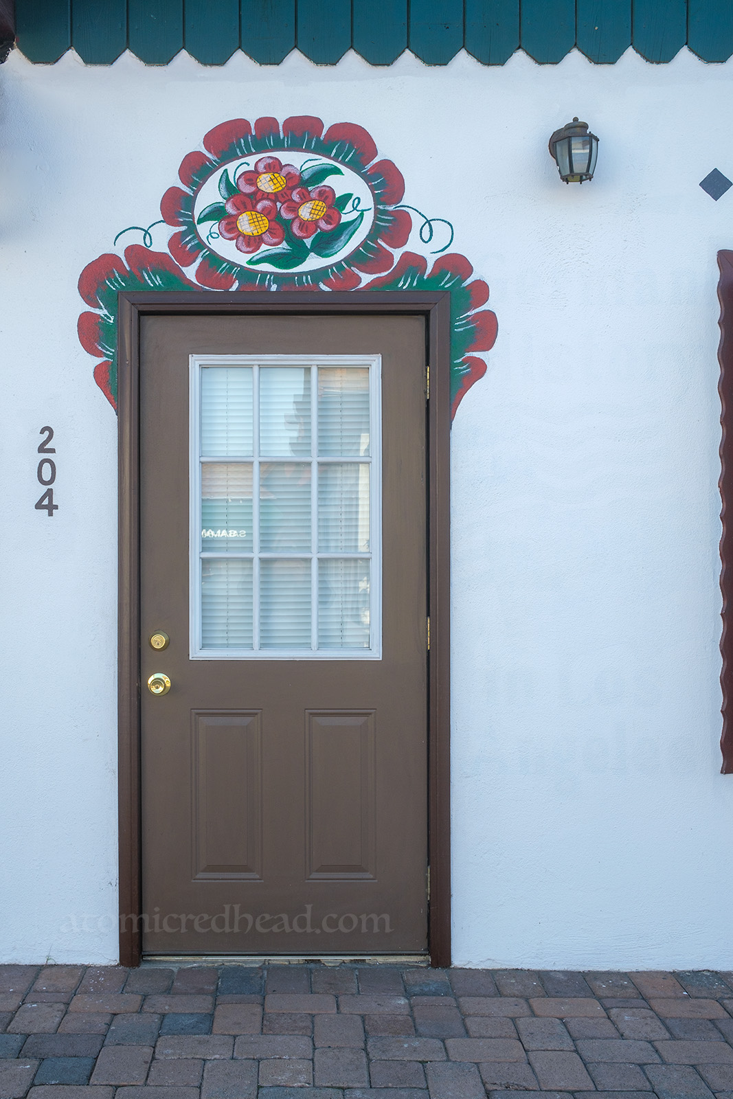 A fanciful floral painting frames a brown door.