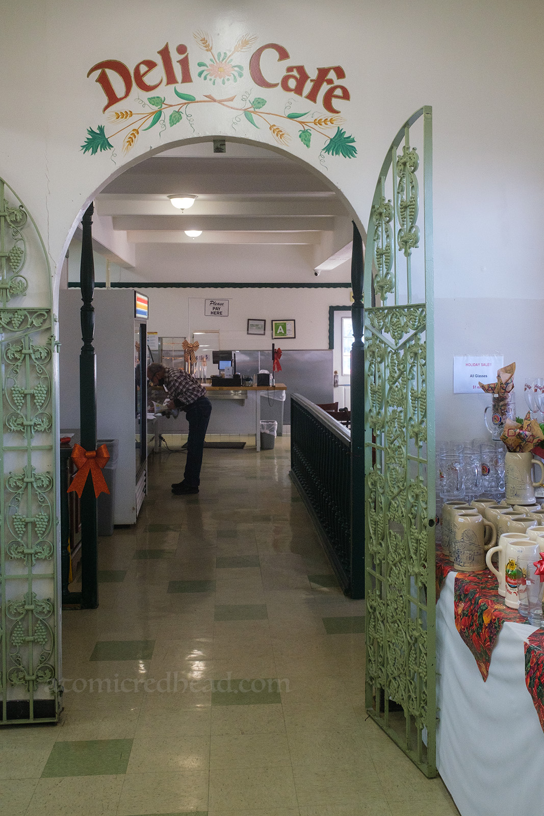 An archway features an open gate, above "Deli Cafe" is painted in red letters, and leads to the attached cafe.