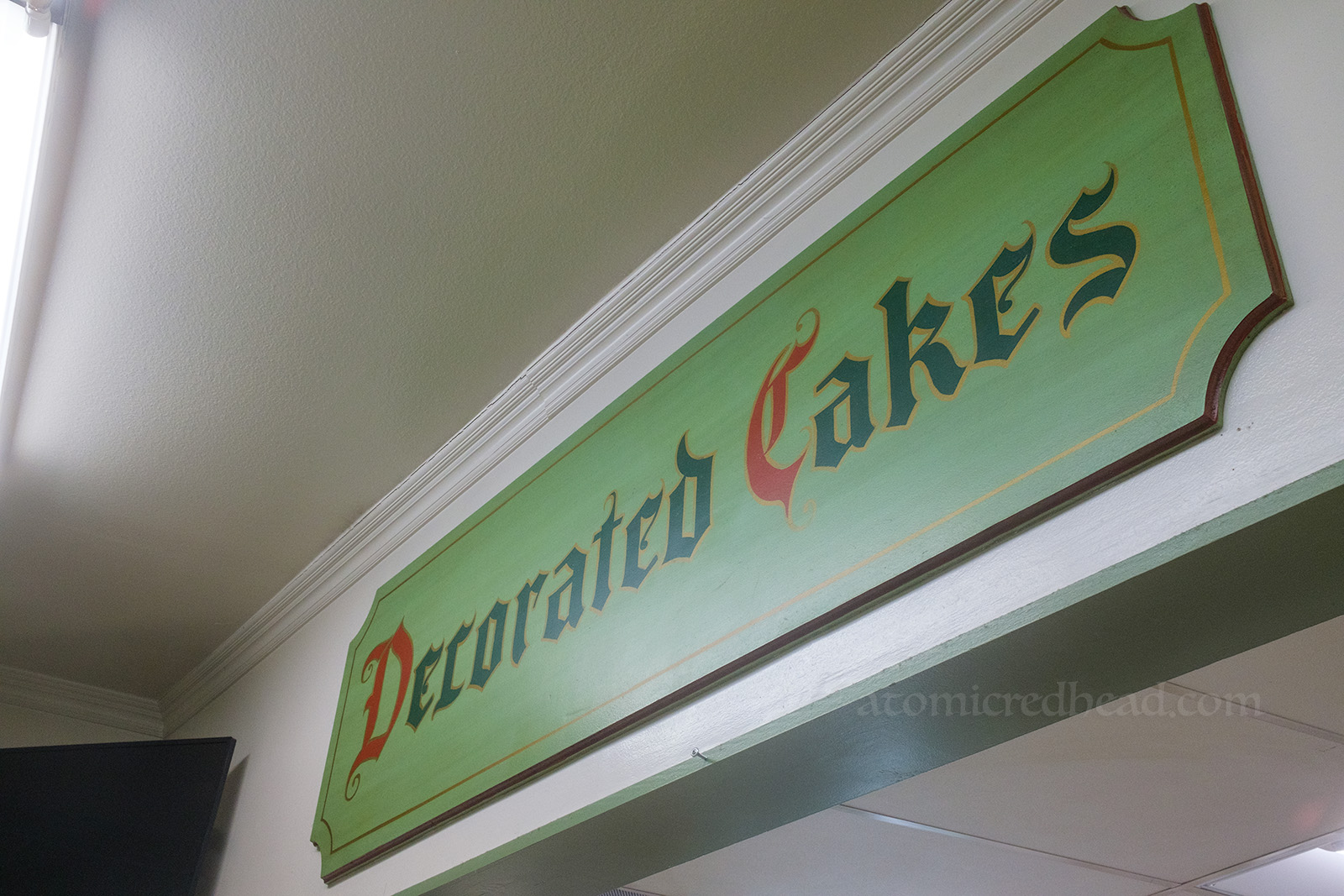 A large green sign, hand painted to read "Decorated Cakes"