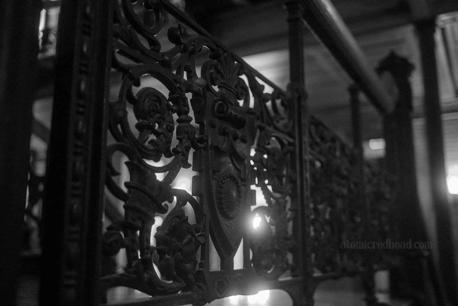 Black and white close-up of swirling wrought iron balcony detail.