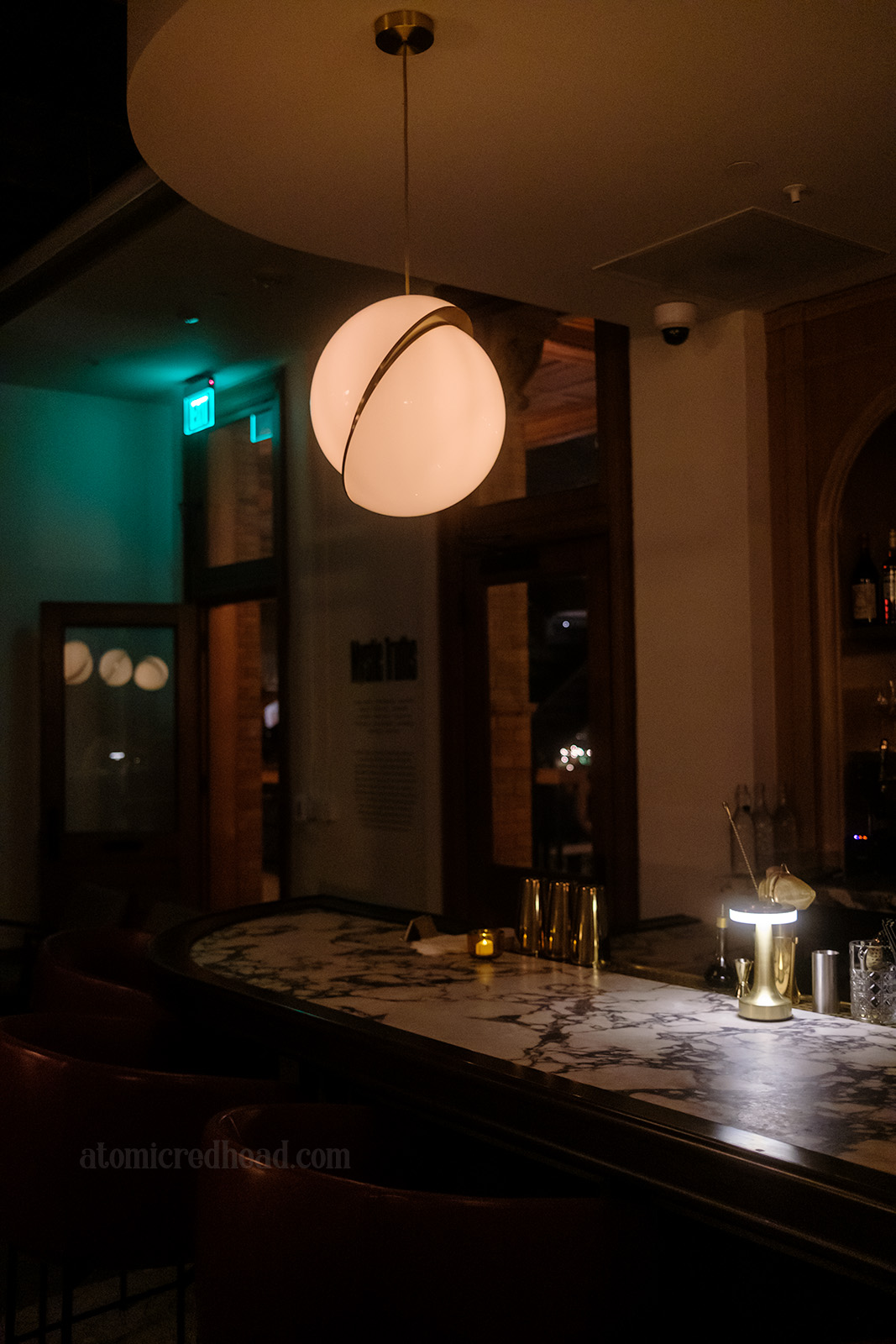 Corner of the bar, which features a marble top, and a globe light fixture hanging above.