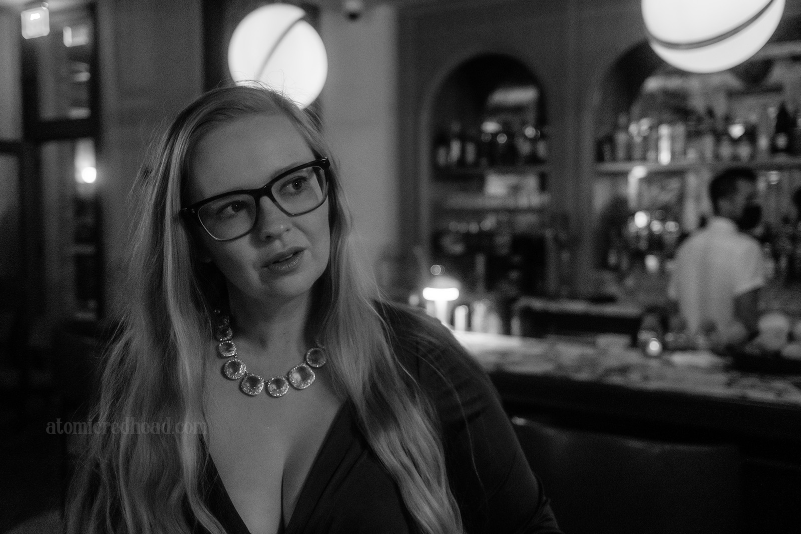 Myself standing in front of the bar, the globe light fixtures hang behind me.