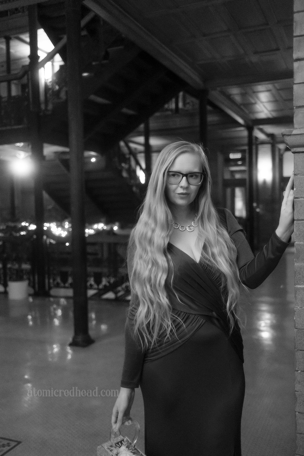 Black and white photo of myself with the zig-zag staircase behind me.