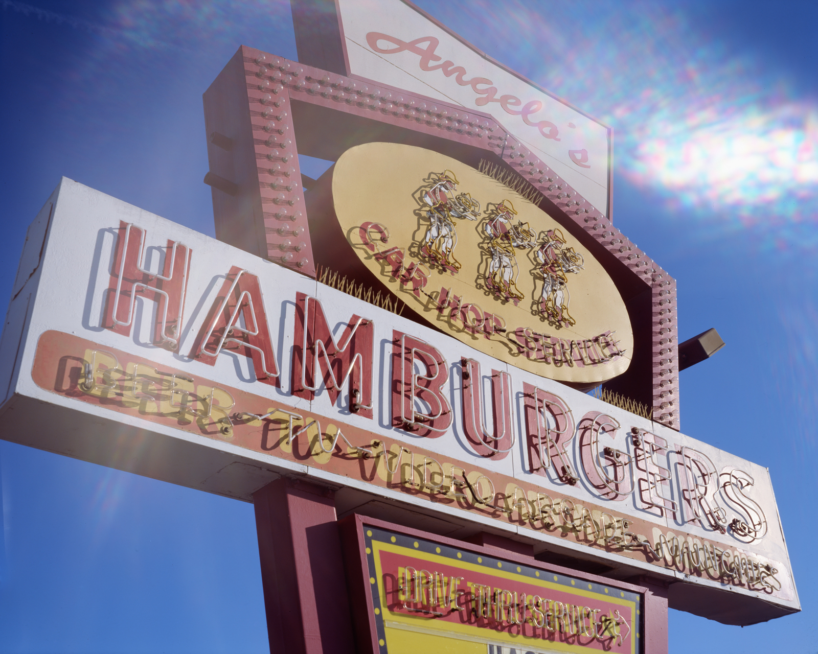 Photograph of a large neon sign reading "Angelo's Car Hop Service Hamburgers"