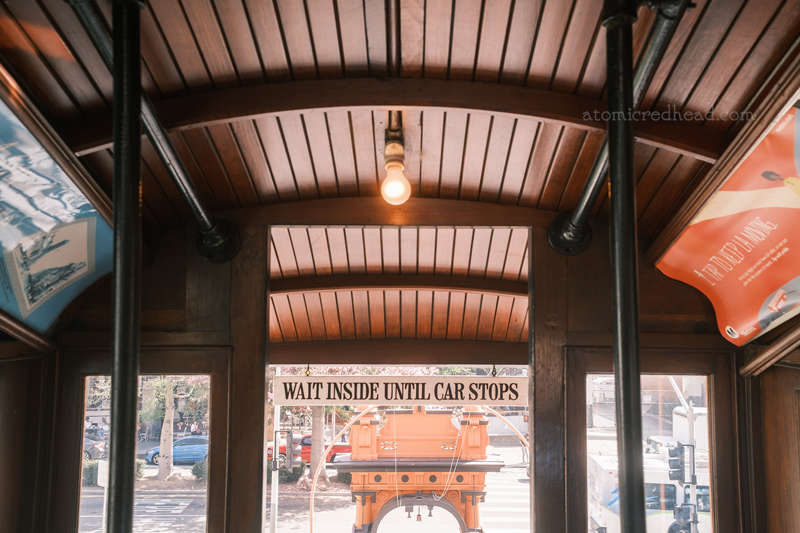 Aboard Angels Flight, dark wood paneled interior. A sign above the doorway reads "Wait Inside Until Car Stops"