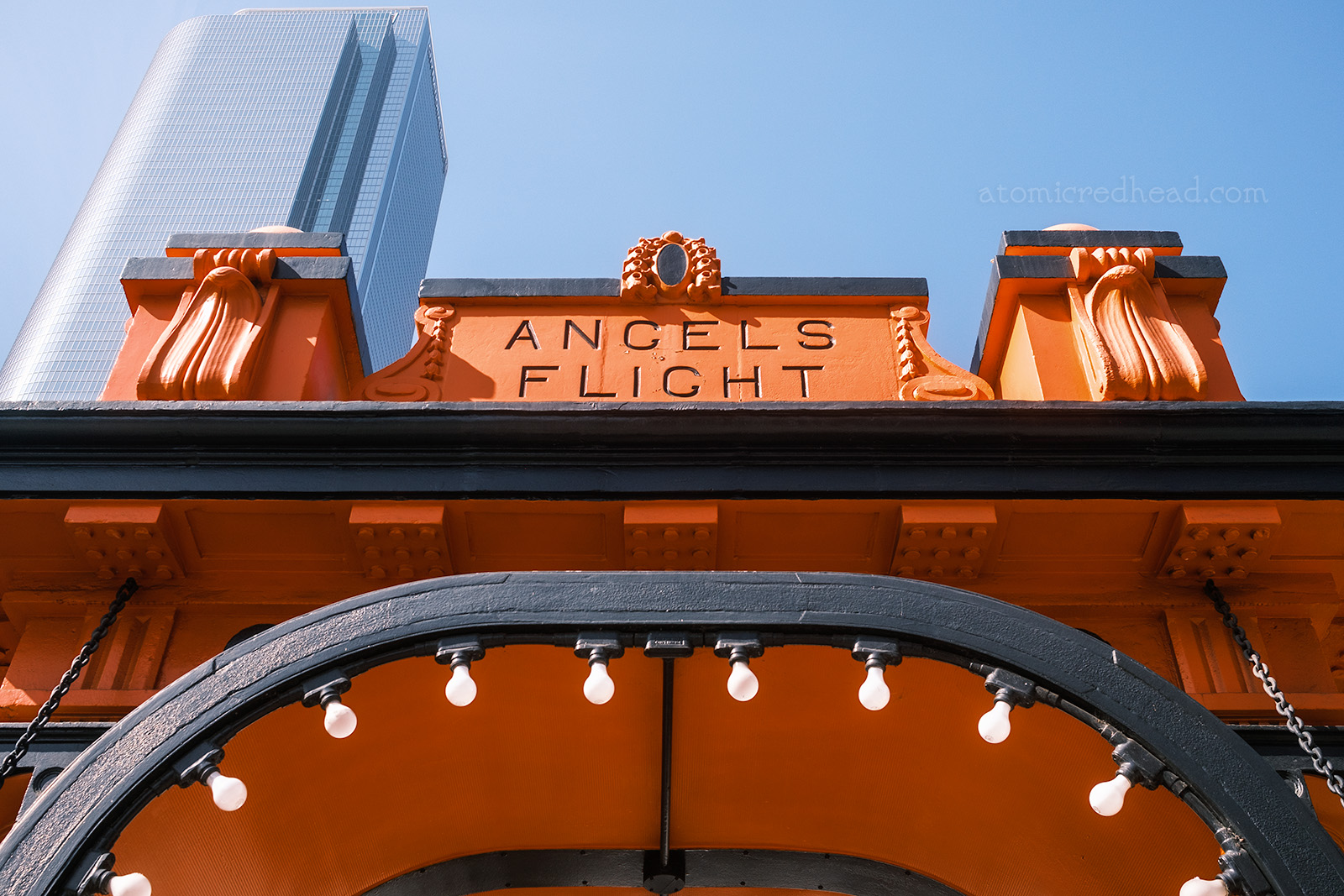 The Hill Street Station arch, which is orange with black trim. Bulbs flank the archway. Letters at the top read "Angels Flight"