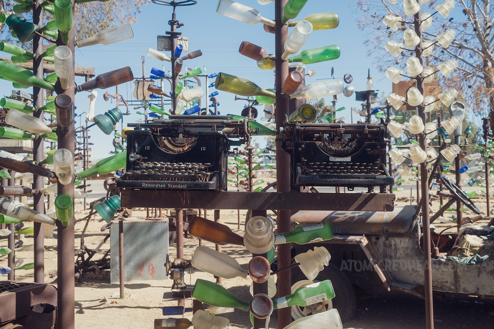 Two typewriters top a shorter bottle tree.