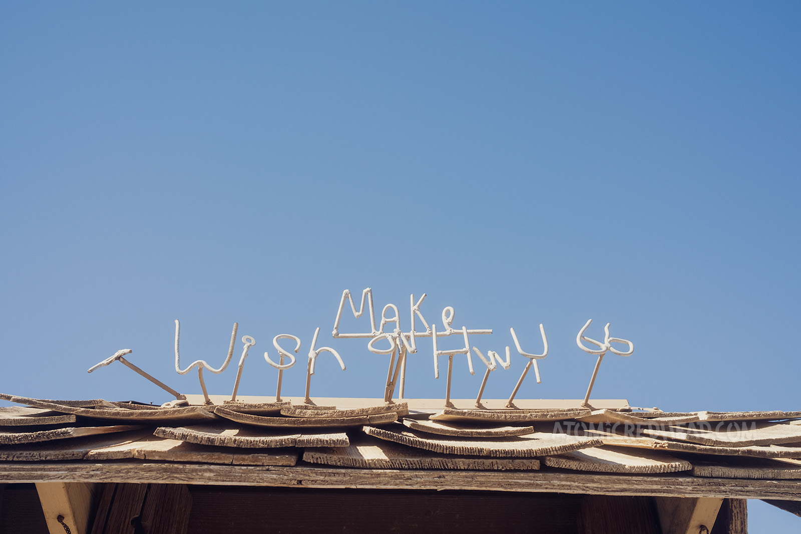 Metal rods bent to read "Make A Wish on Hwy 66" sit atop a wishing well.