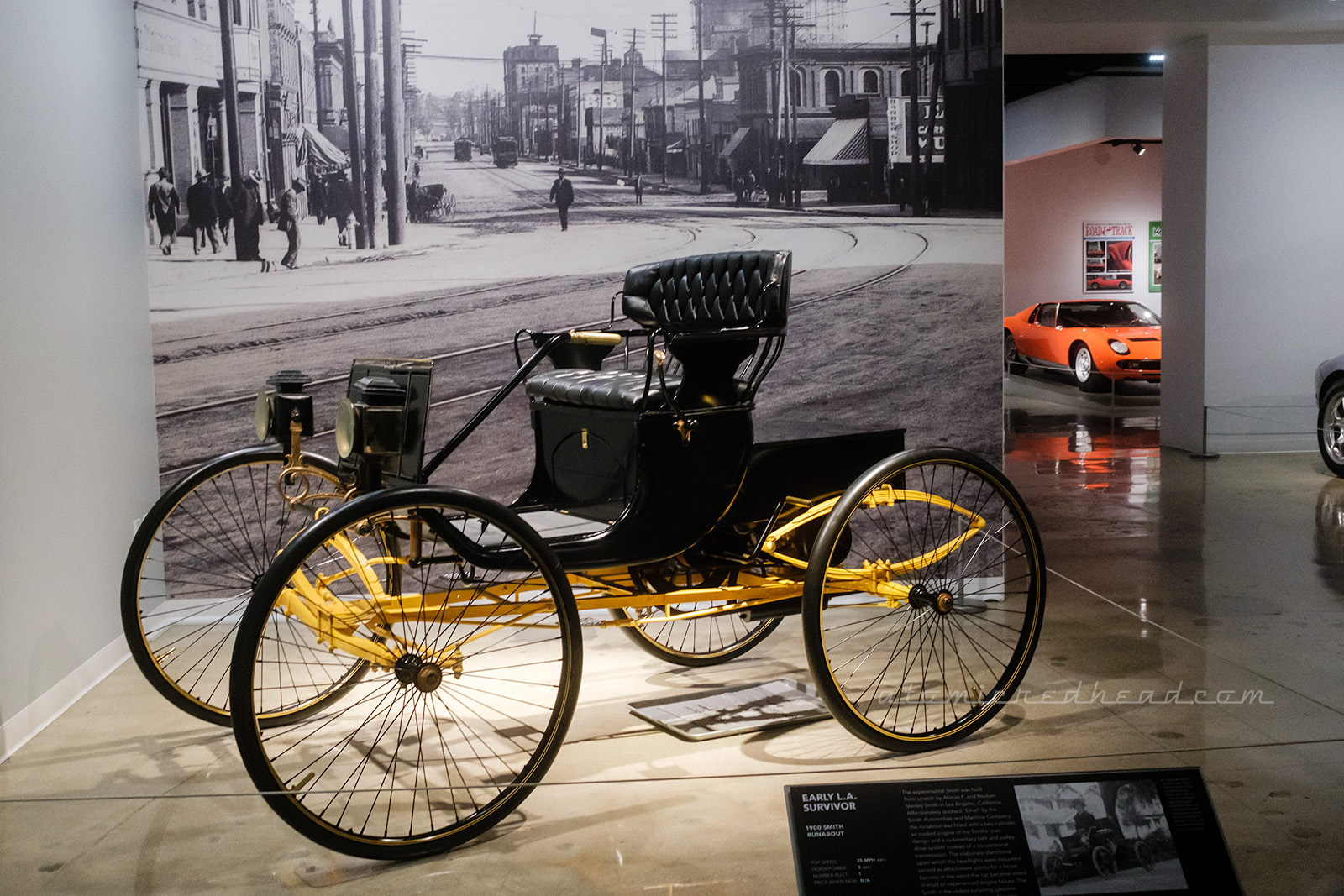 A 1900 Smith Runabout, known here as an "early LA survivor" as it was hand made in LA. An open carriage, with four narrow wheels and a small handle to steer.