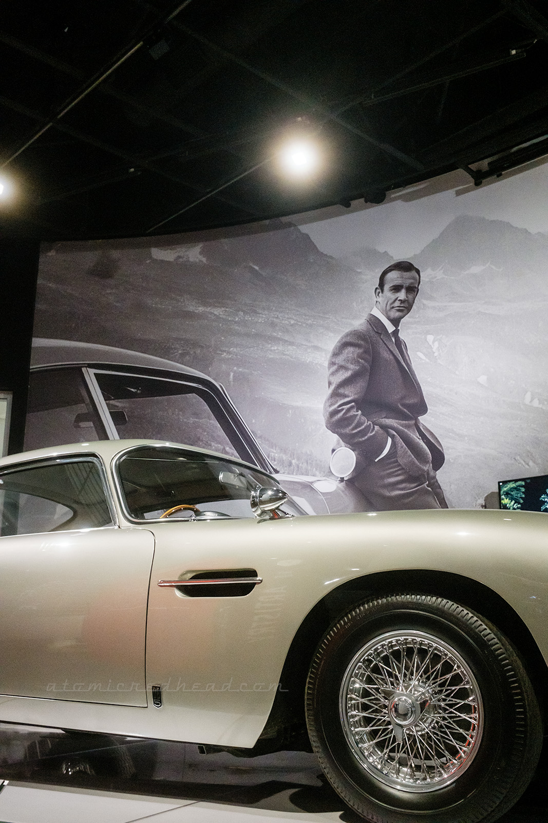 The classic silver 1964 Aston Martin DB5, as seen in various James Bond films. Behind it a photo of Sean Connery as James Bond.