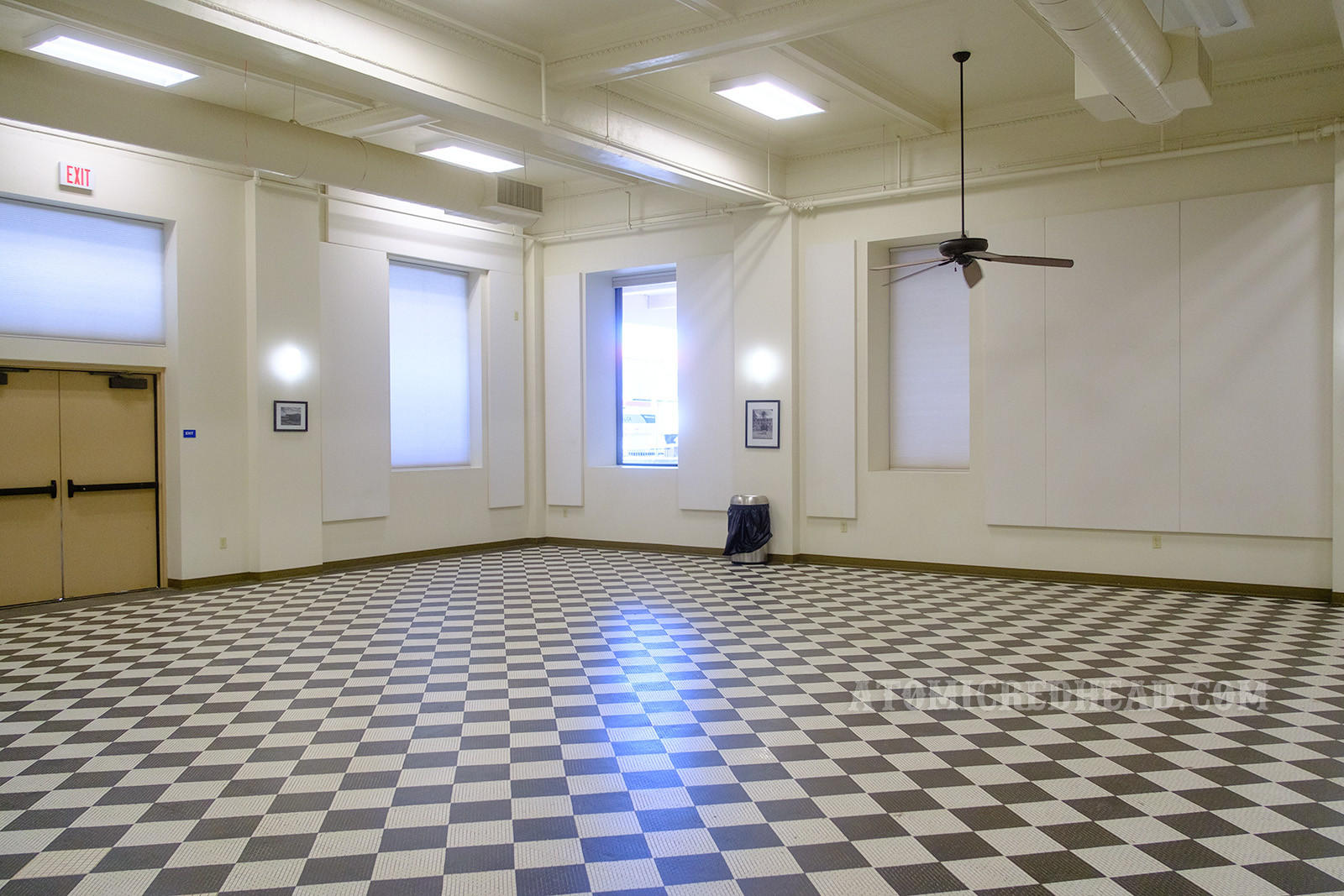 The former dining room of the El Garces, which features black and white checkered tile, the walls are painted white, fans hang from the sceeling.