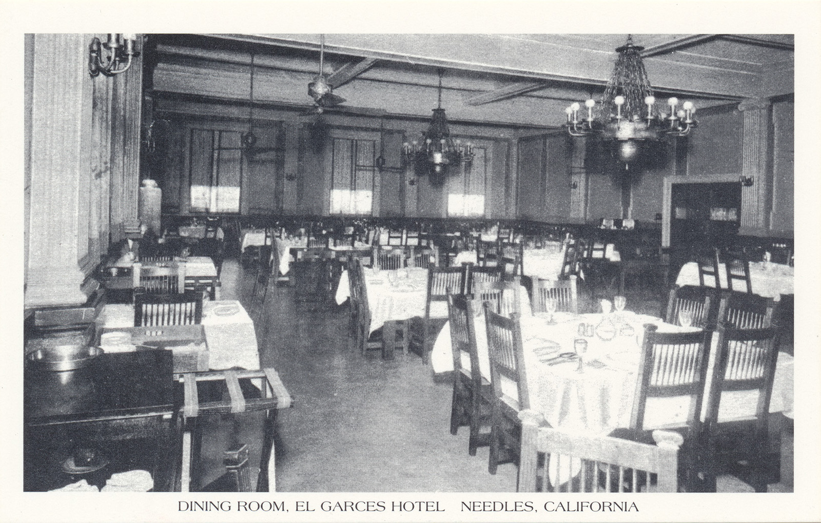 Postcard of a vintage photograph of the original dining room, featuring chandeliers, tables with white linens.