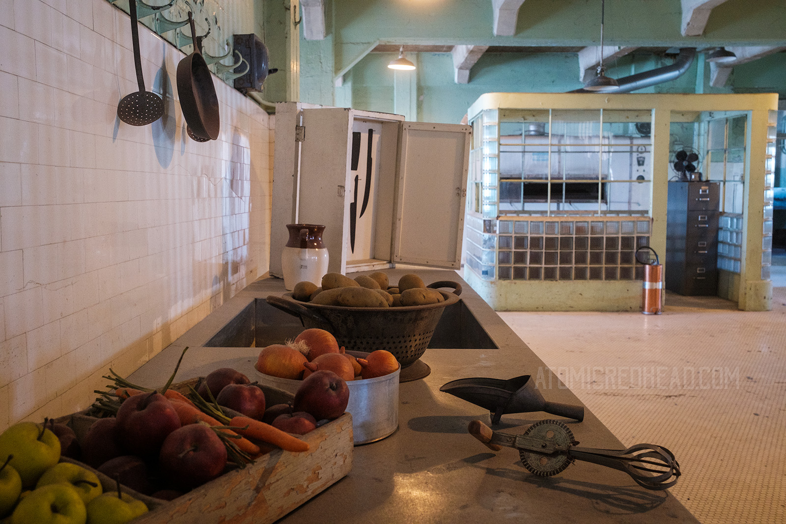 Inside the kitchen, with counters full of food, and cabinet which would keep knives.