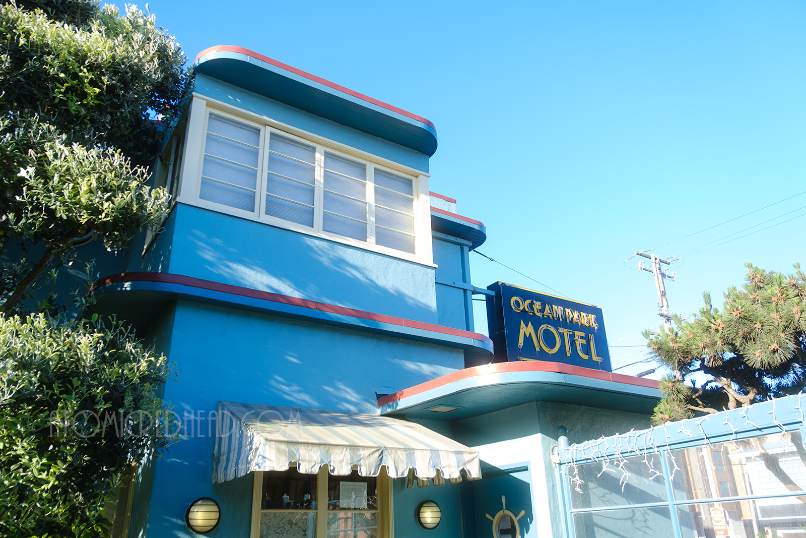 Flat curved edge roof of the motel, above the office window. The side of the model is painted a deep sky blue with red trim along the roof edge, with the windows painted in white trim.