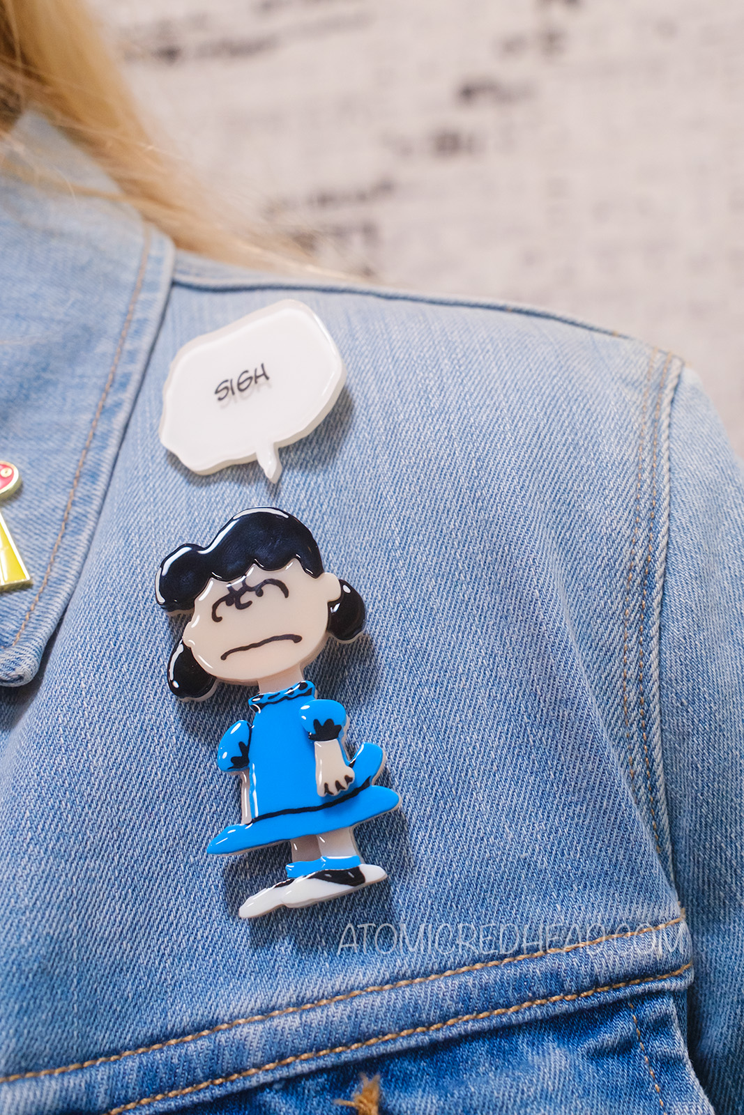 Close-up of my brooches, which feature Lucy in her iconic blue dress, and a text bubble reading "Sigh"